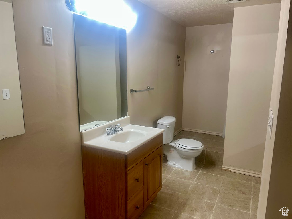 Half bathroom with toilet, vanity, and tile patterned flooring