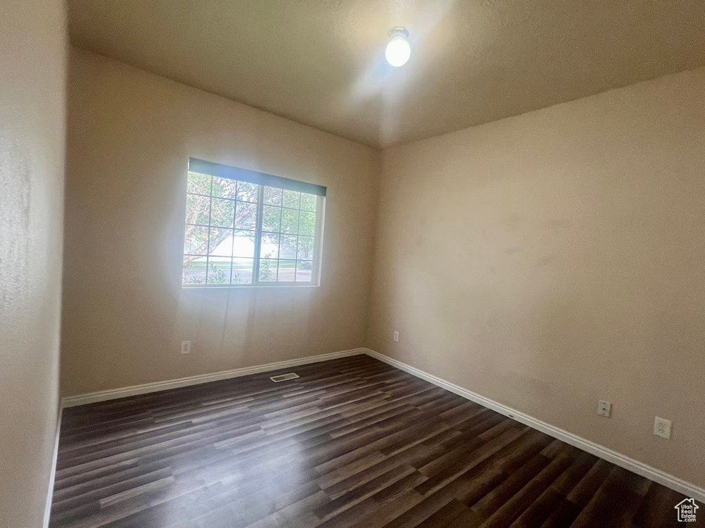 Spare room with dark wood finished floors and baseboards