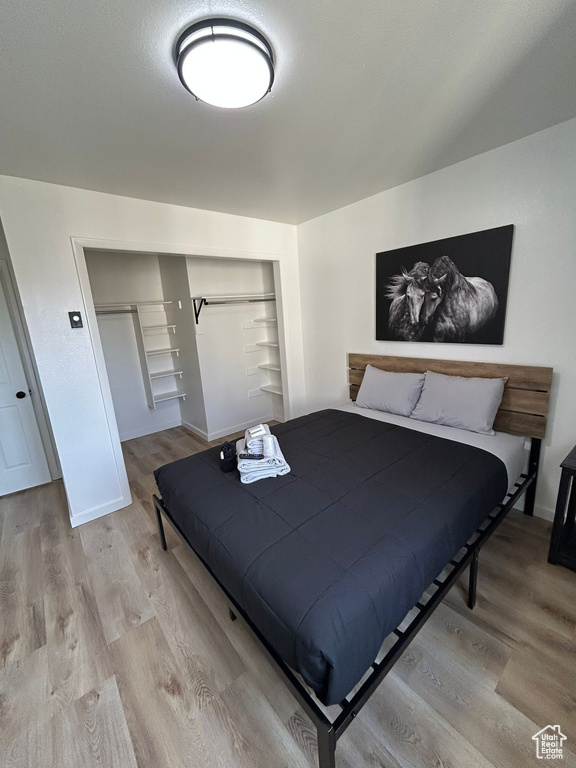 Bedroom with light wood-style floors, a closet, and baseboards