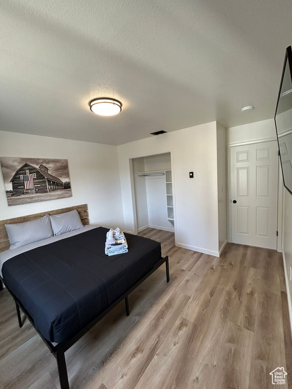 Bedroom featuring a textured ceiling, light wood-style floors, a closet, and baseboards