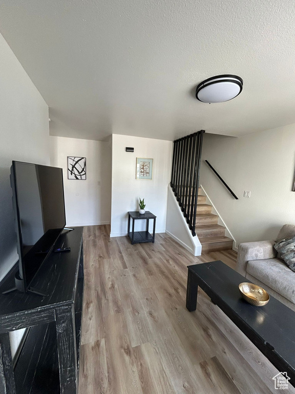 Living room featuring stairway, light wood finished floors, and a textured ceiling