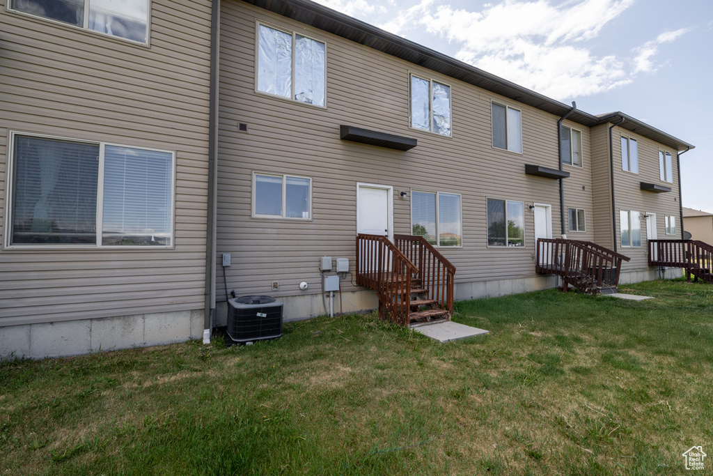 Rear view of house with cooling unit and a yard