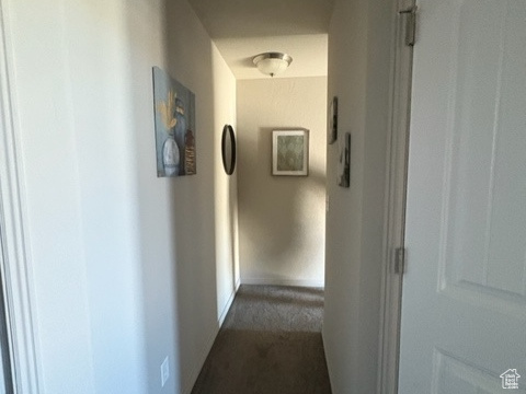 Corridor with dark carpet and baseboards