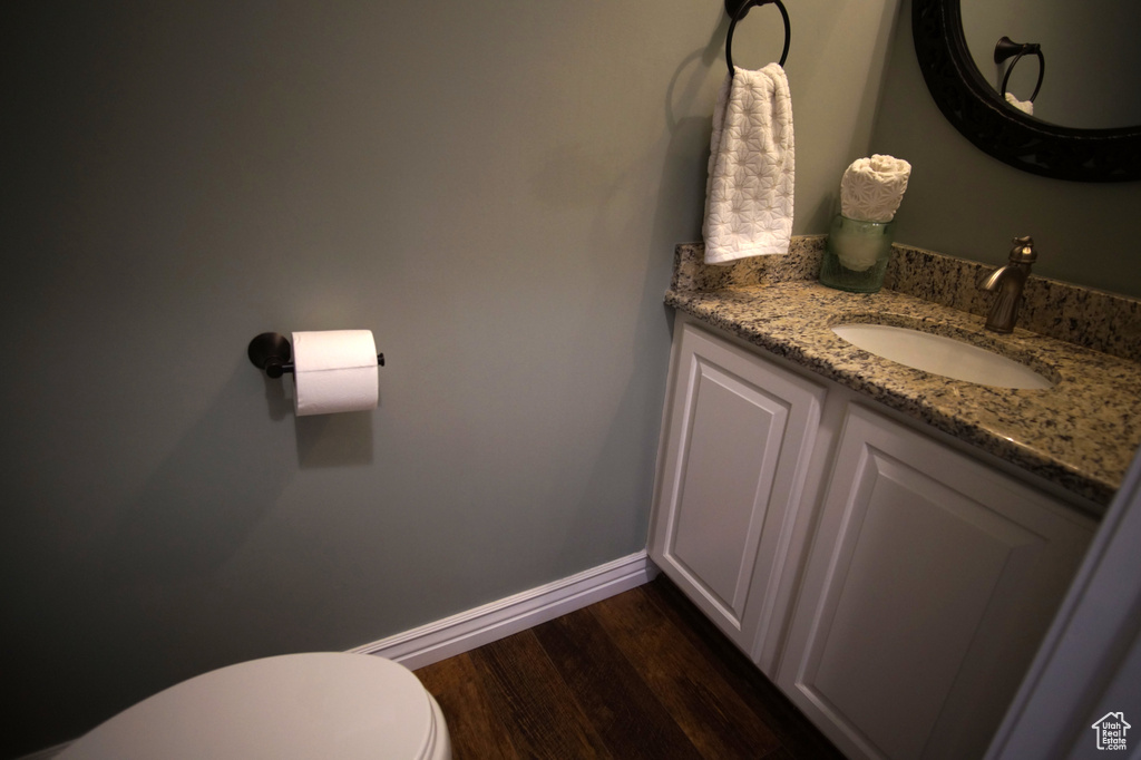 Bathroom featuring vanity, toilet, wood finished floors, and baseboards