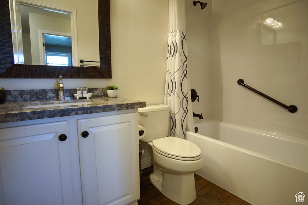 Bathroom with vanity, toilet, shower / tub combo, and wood finished floors