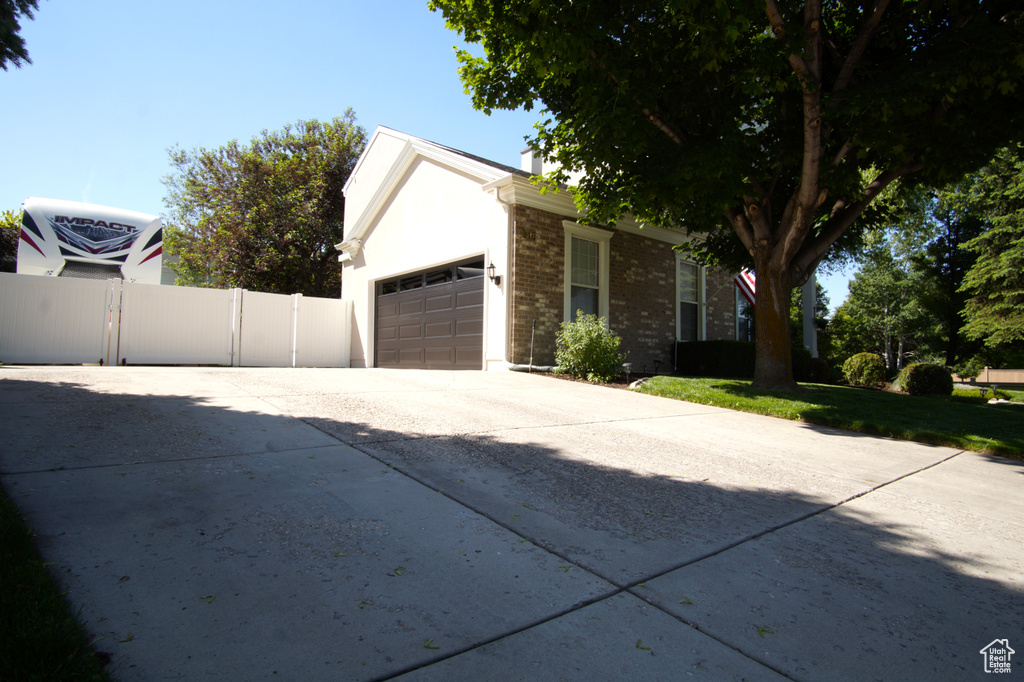 View of front of property featuring driveway, an attached garage, and brick siding