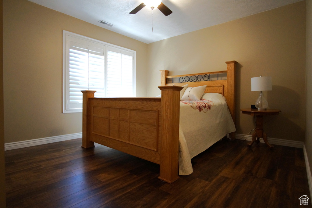 Bedroom featuring dark wood-style floors, baseboards, and ceiling fan