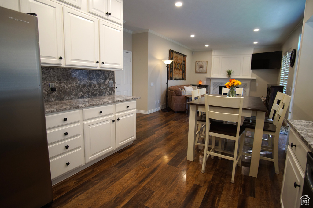Kitchen with freestanding refrigerator, recessed lighting, backsplash, open floor plan, and dark wood-style floors