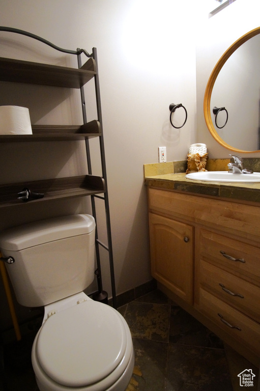Half bath featuring vanity, toilet, and tile patterned flooring