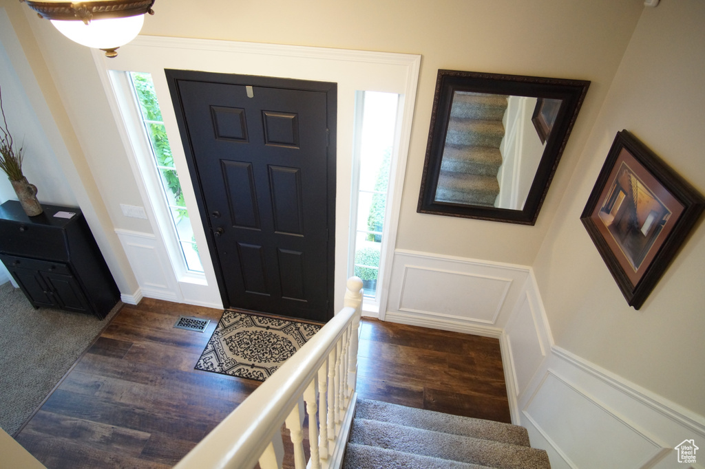 Foyer featuring wood finished floors, a decorative wall, a wainscoted wall, and stairway