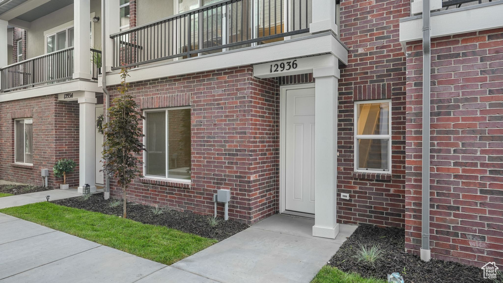 View of exterior entry with a balcony and brick siding