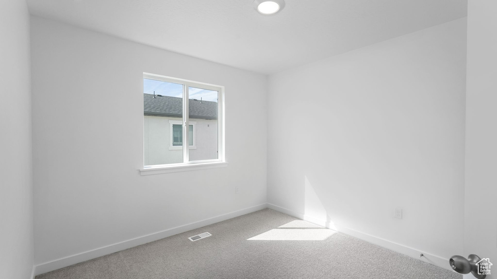 Carpeted spare room featuring baseboards