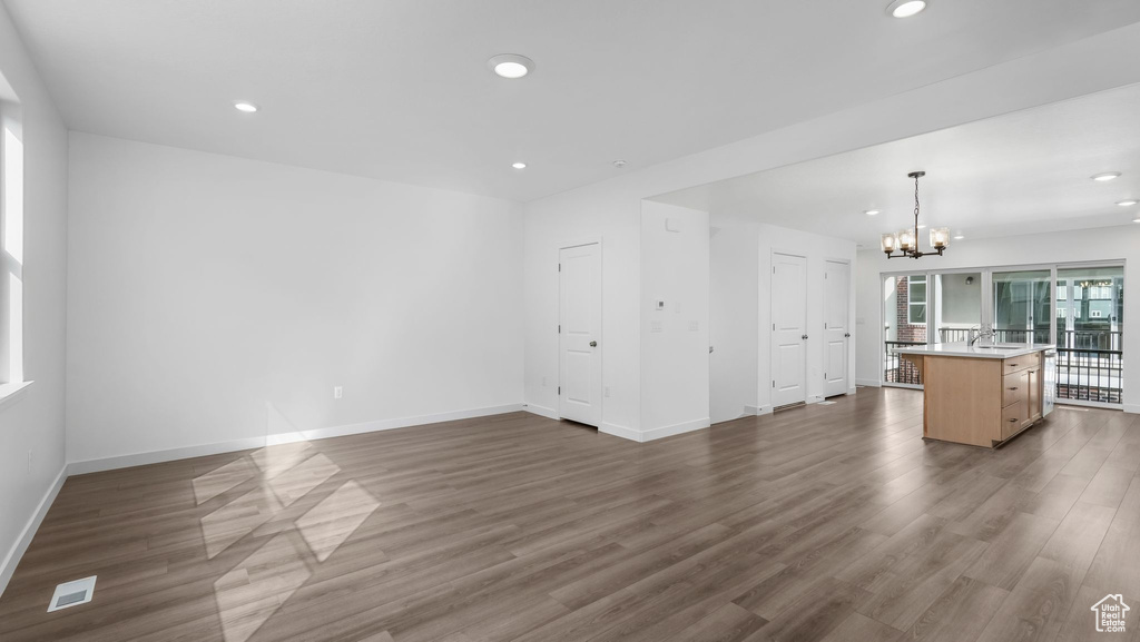 Unfurnished living room with a chandelier, dark wood finished floors, and recessed lighting