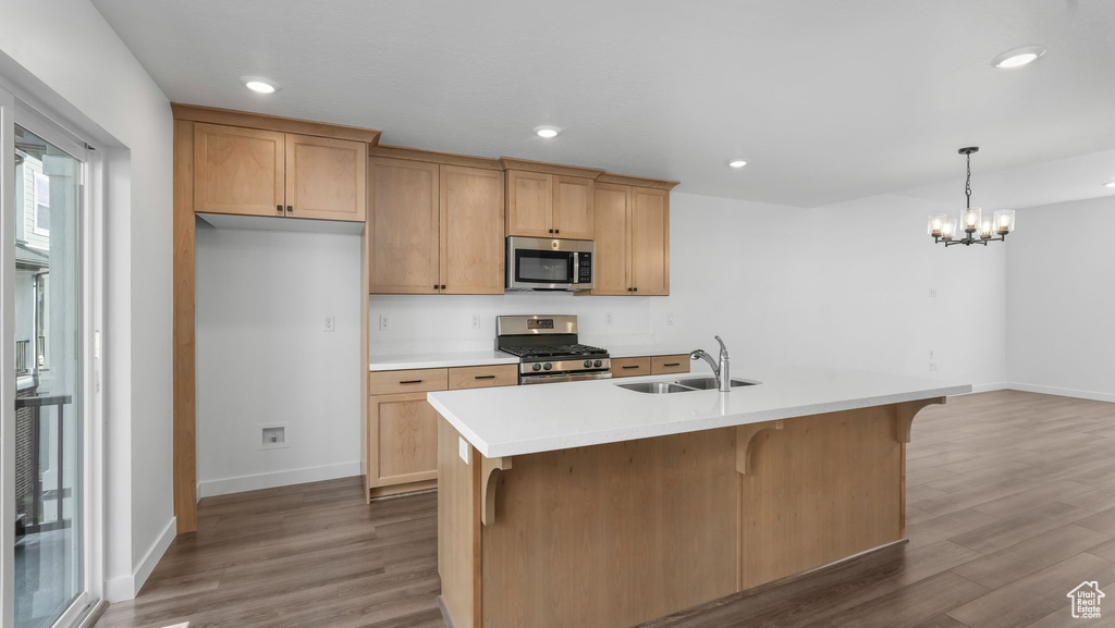 Kitchen with appliances with stainless steel finishes, wood finished floors, a chandelier, light countertops, and recessed lighting