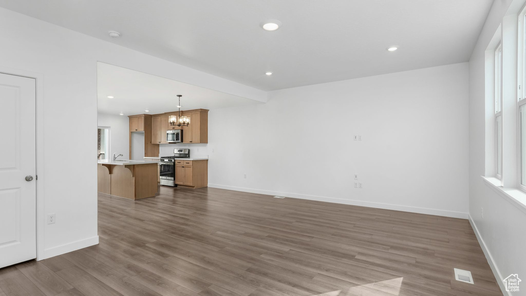 Unfurnished living room with a chandelier, wood finished floors, and recessed lighting