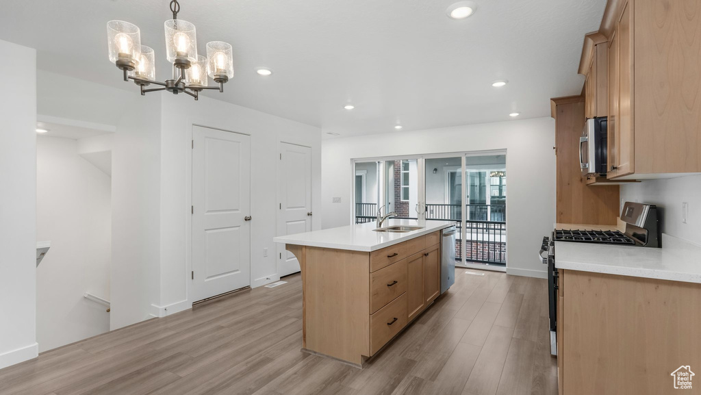 Kitchen featuring stainless steel appliances, light wood-style floors, a center island with sink, light brown cabinetry, and recessed lighting