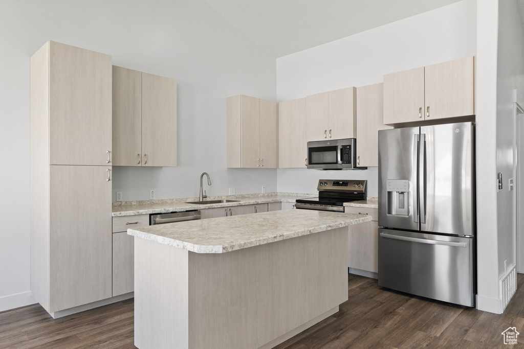 Kitchen with stainless steel appliances, dark wood-type flooring, light countertops, a center island, and light brown cabinets