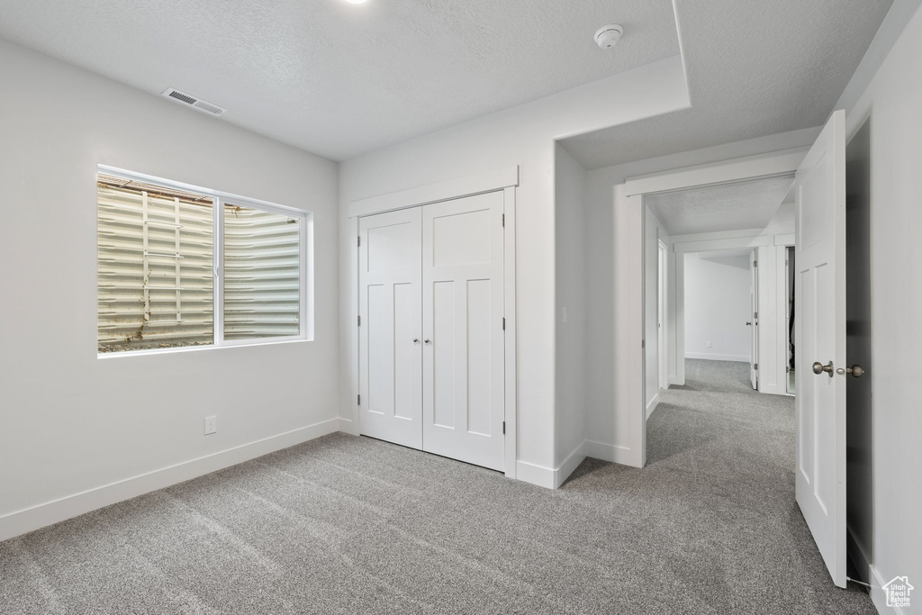 Unfurnished bedroom with carpet flooring, a closet, and a textured ceiling