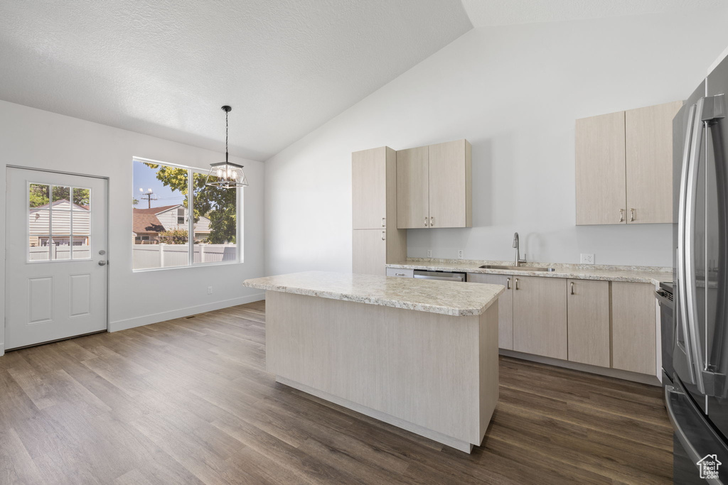 Kitchen with light brown cabinetry, a chandelier, stainless steel appliances, dark wood-type flooring, and high vaulted ceiling