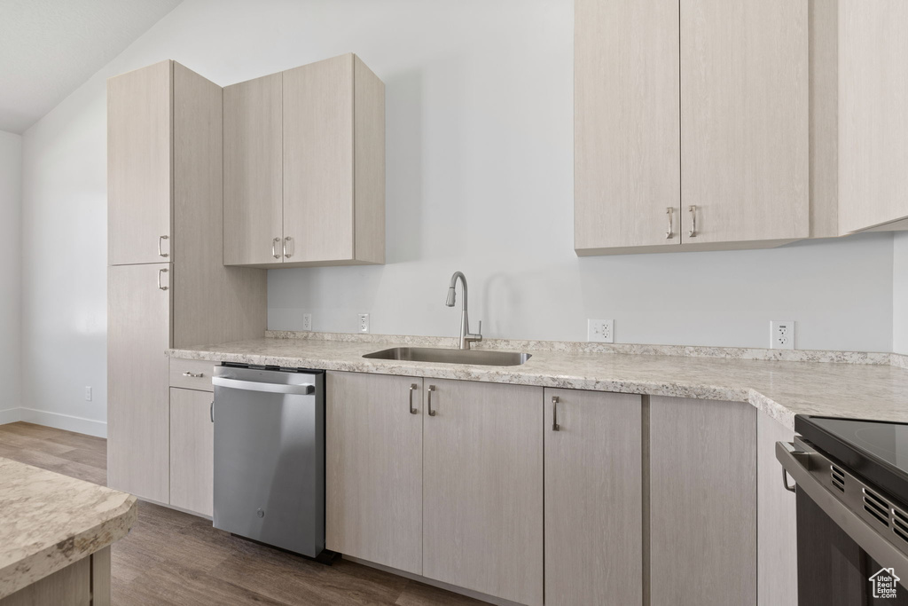 Kitchen with dishwasher, wood finished floors, light brown cabinets, and range