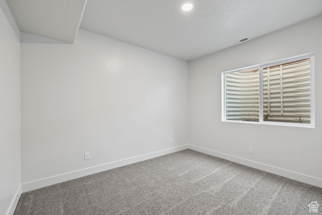 Carpeted spare room featuring baseboards