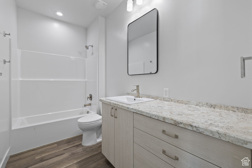 Full bathroom featuring vanity, wood finished floors, and washtub / shower combination
