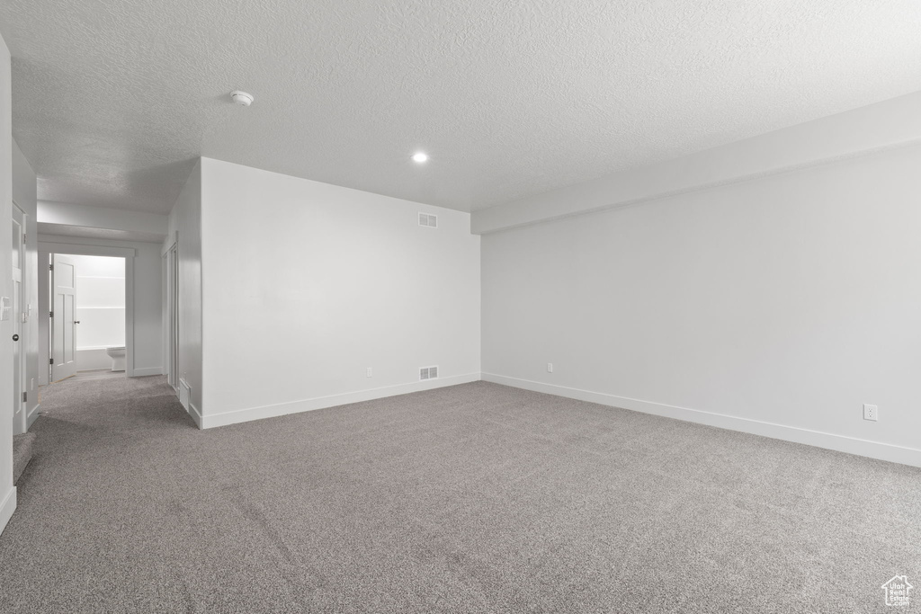 Carpeted spare room featuring a textured ceiling and recessed lighting