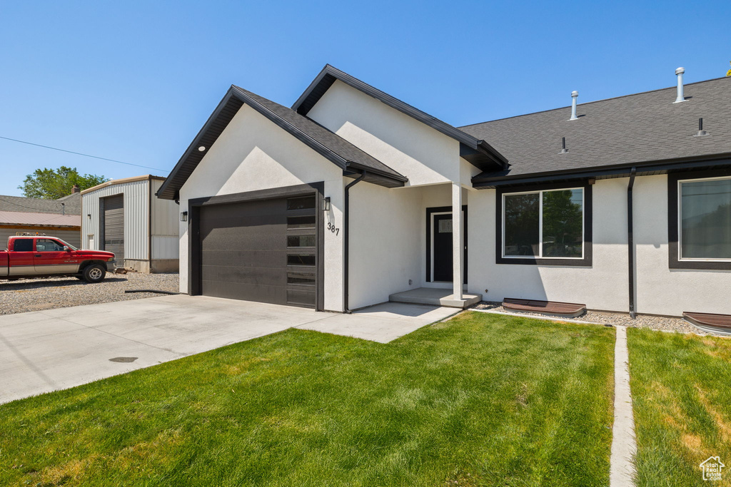 Ranch-style home featuring a garage, driveway, a front yard, and stucco siding