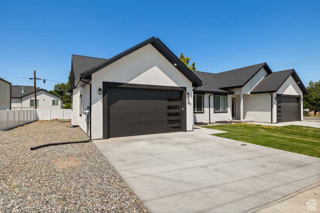 View of front of property featuring an attached garage, stucco siding, and driveway