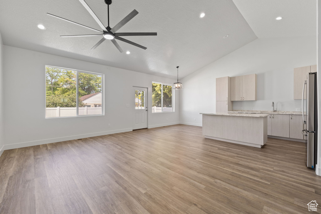 Unfurnished living room with ceiling fan, lofted ceiling, light wood-style floors, and recessed lighting
