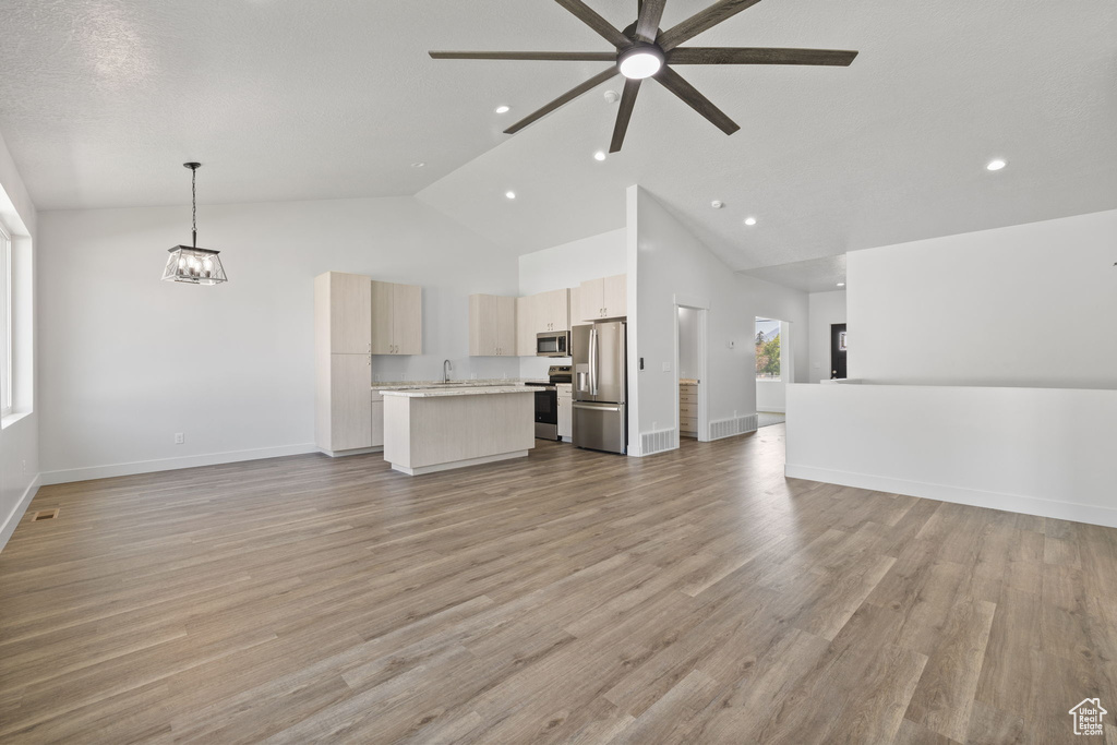 Unfurnished living room with high vaulted ceiling, recessed lighting, a ceiling fan, light wood-type flooring, and a chandelier