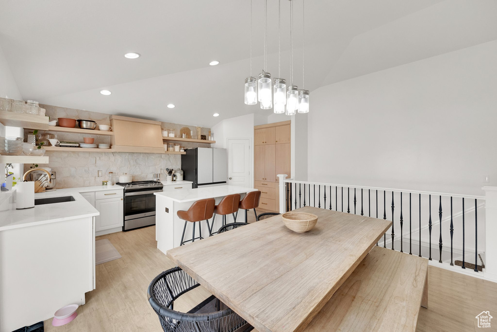 Dining area with light wood finished floors, vaulted ceiling, and recessed lighting