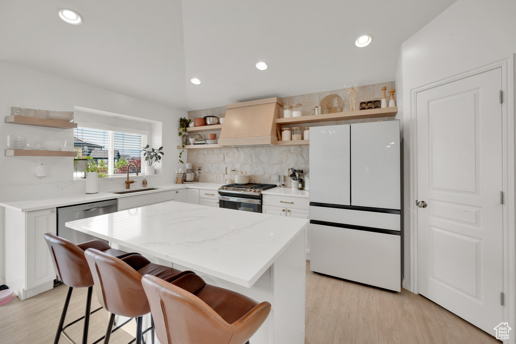 Kitchen featuring open shelves, stainless steel appliances, custom exhaust hood, a sink, and backsplash