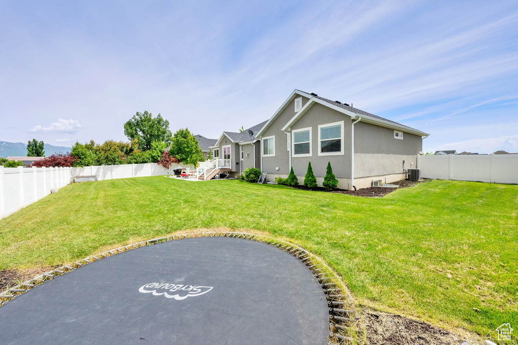 Rear view of property with stucco siding and central AC