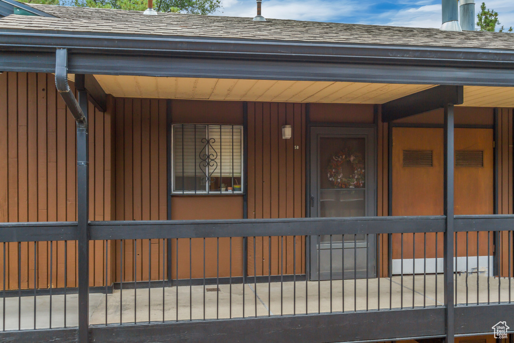 Doorway to property featuring roof with shingles