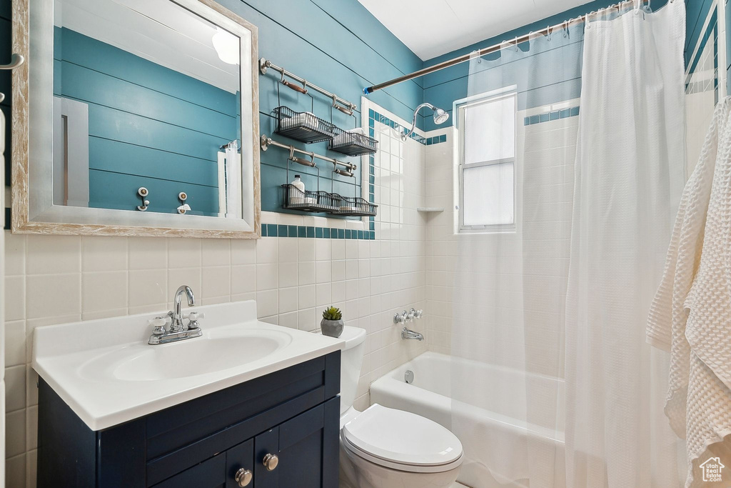 Bathroom featuring tile walls, shower / bath combo, vanity, and toilet