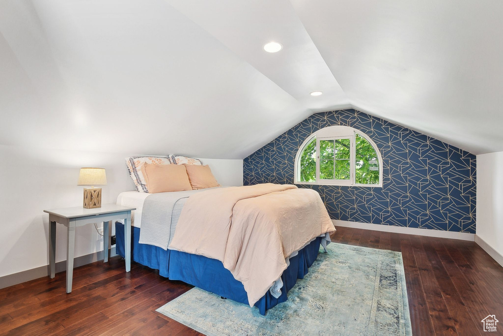 Bedroom featuring hardwood / wood-style floors, vaulted ceiling, and baseboards