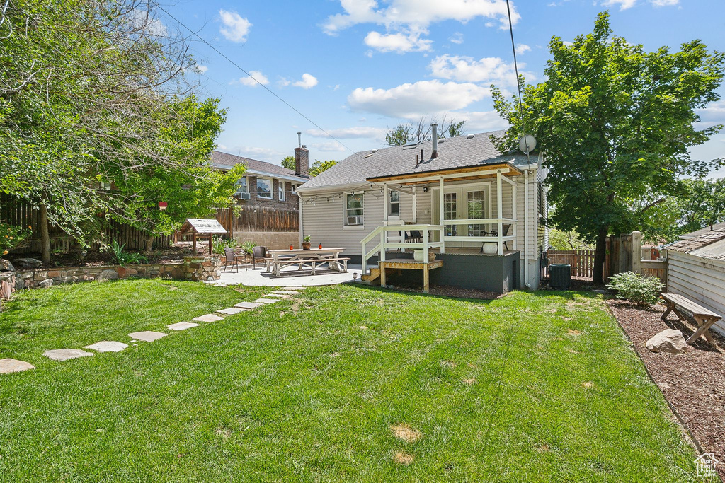 Rear view of property featuring a patio, a wooden deck, and roof with shingles