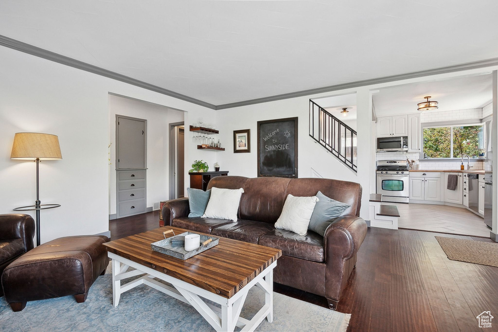 Living room with stairs, wood finished floors, and crown molding
