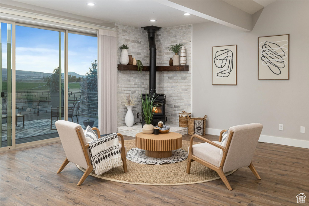 Sitting room with wood finished floors, a wood stove, baseboards, and recessed lighting