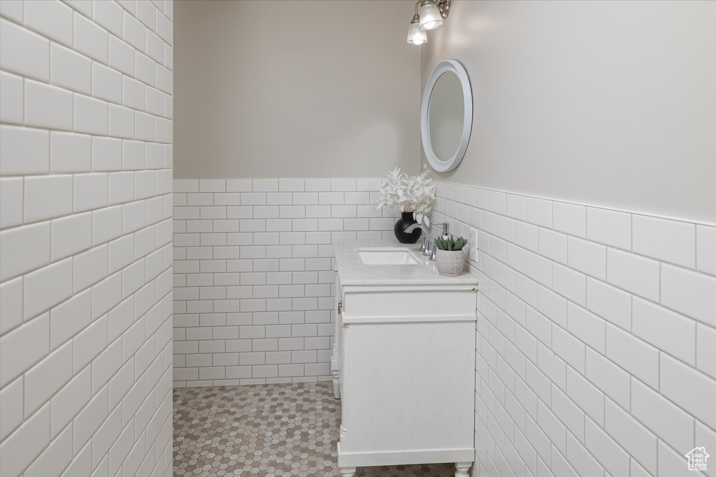 Bathroom with tile walls, vanity, a wainscoted wall, and tile patterned floors