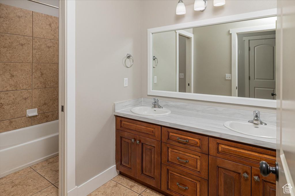 Full bathroom featuring double vanity, tile patterned flooring, baseboards, and shower / washtub combination
