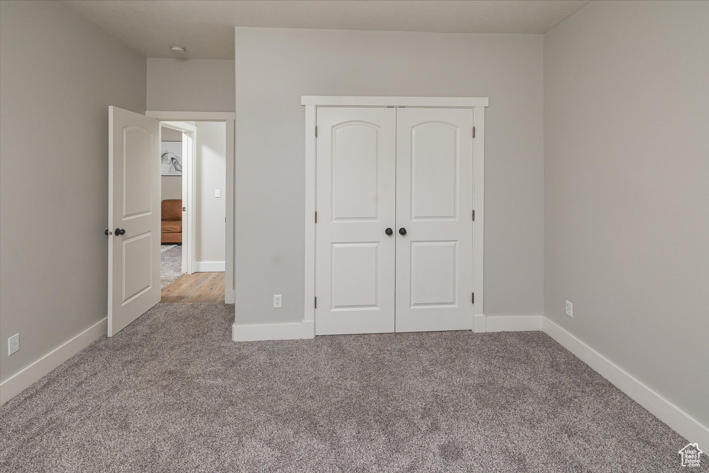 Unfurnished bedroom with carpet floors, a closet, and baseboards