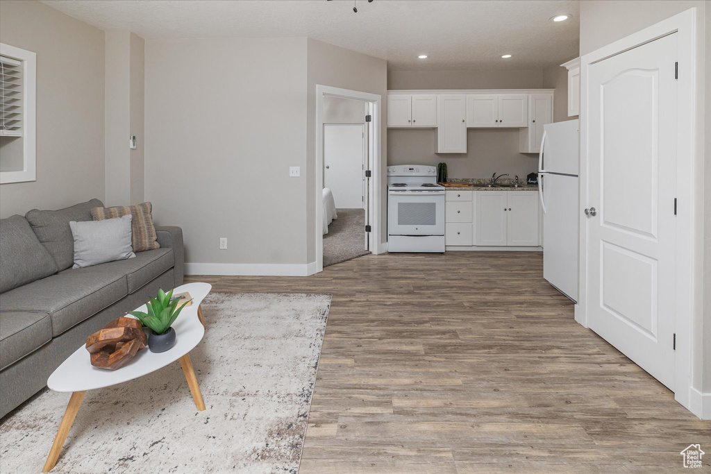 Living area with light wood-type flooring, recessed lighting, and baseboards