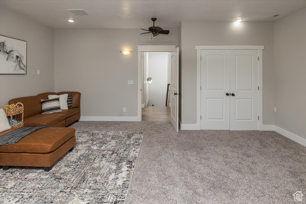 Carpeted living room featuring a ceiling fan and baseboards