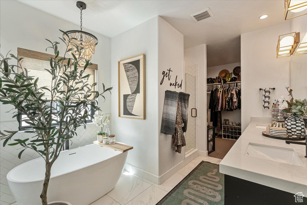 Bathroom with a soaking tub, double vanity, a spacious closet, and a chandelier