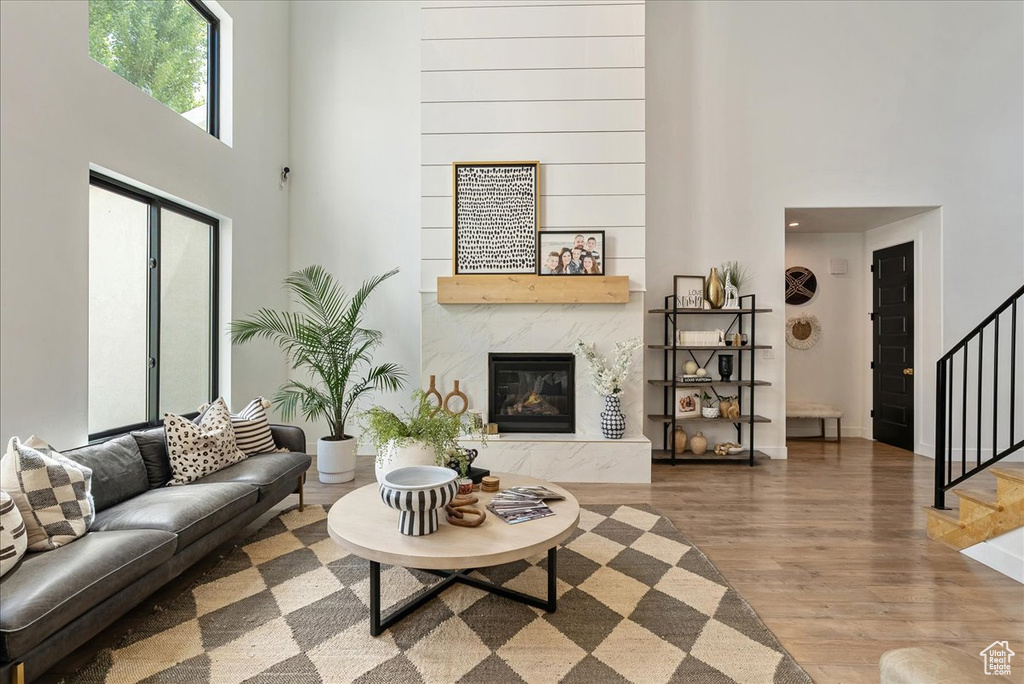 Living area with a towering ceiling, stairs, wood finished floors, a fireplace, and baseboards