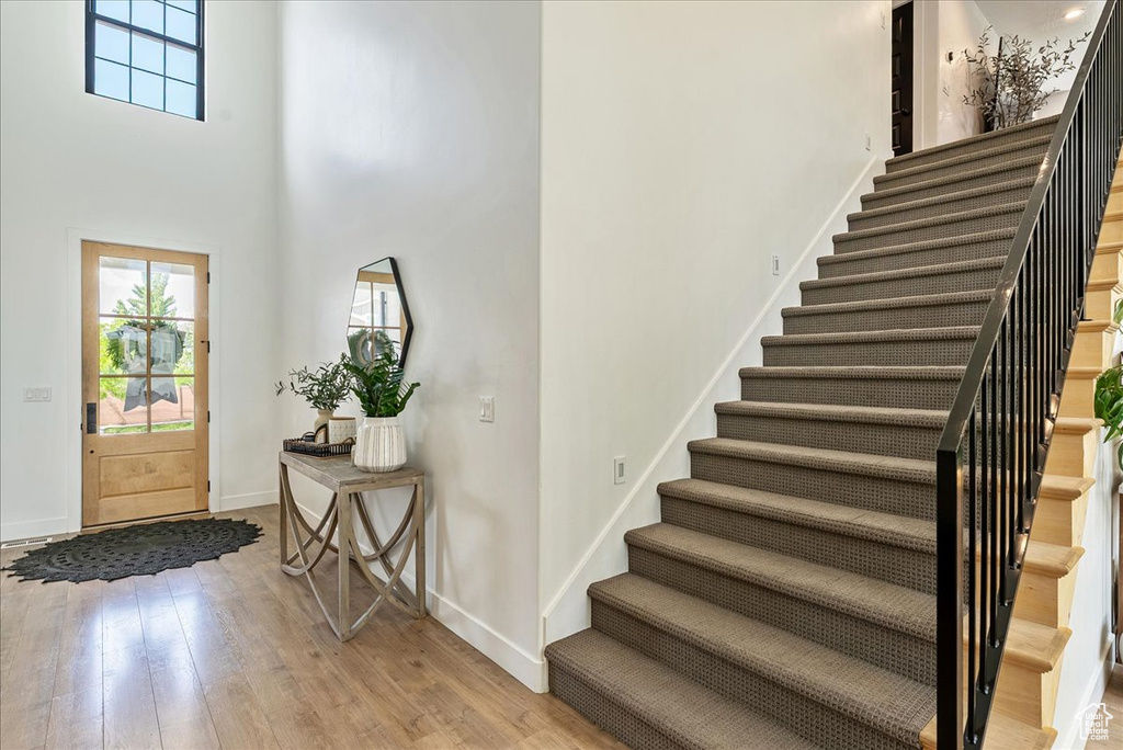 Foyer entrance featuring stairs, plenty of natural light, light wood-style floors, baseboards, and a towering ceiling