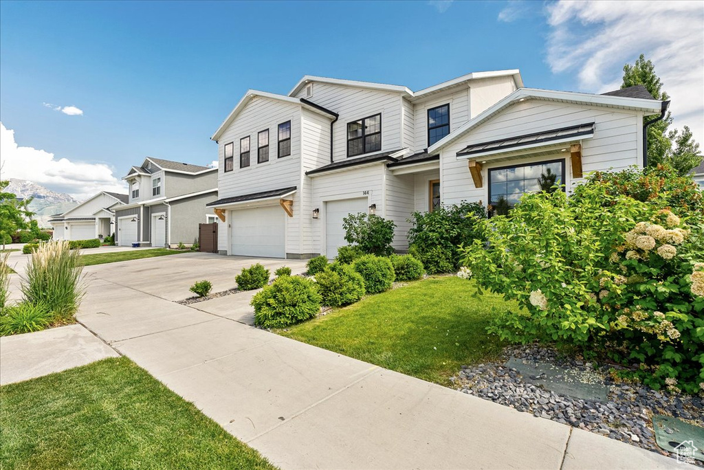 View of front facade featuring a garage, driveway, a front yard, and a residential view