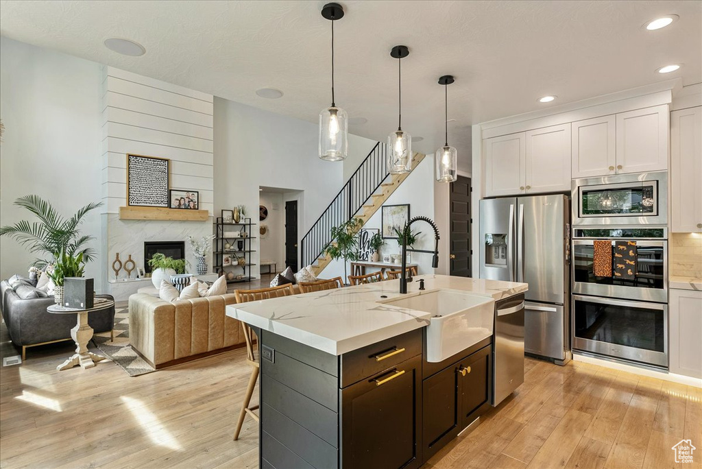 Kitchen with a sink, stainless steel appliances, light wood-style flooring, white cabinets, and recessed lighting
